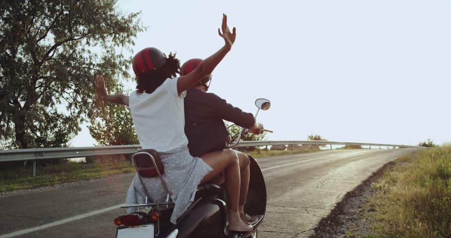 The girl on the motorbike is waving her hands into the air being all excited going on a long distance journey with her lover Royalty-Free Stock Footage #1015501423