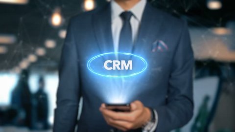Businessman With Mobile Phone Opens Hologram HUD Interface and Touches Word - CRM