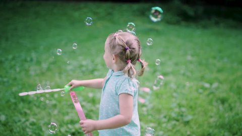 Child Having Fun In Nature. Girl Making Soap Bubbles Outdoors