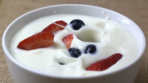 Strawberry and blue berry falling in to yogurt splashing in slow motion. Morning breakfast. 