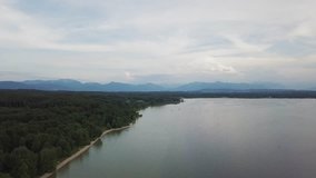 Aerial footage camera flight along the bank of the lake with the mountain on the background 