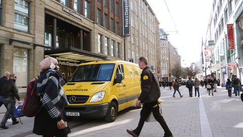 HAMBURG, GERMANY - CIRCA 2018: Employee with steel security box entering cash-in-transit Mercedes-Benz yellow wan central German city Prosegur Compania de Seguridad is a multinational security company