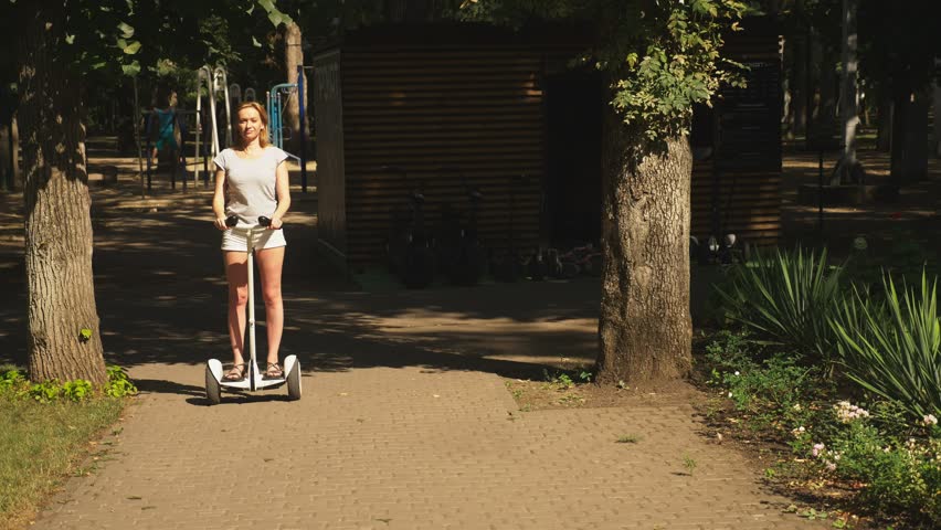 Girl in white shorts, riding a scooter on a clear sunny day. 
