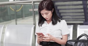business woman sit on chair in MRT station and use phone