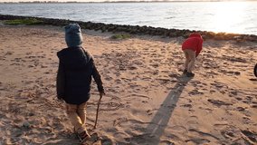 Little brother and sister write words in the sand together
