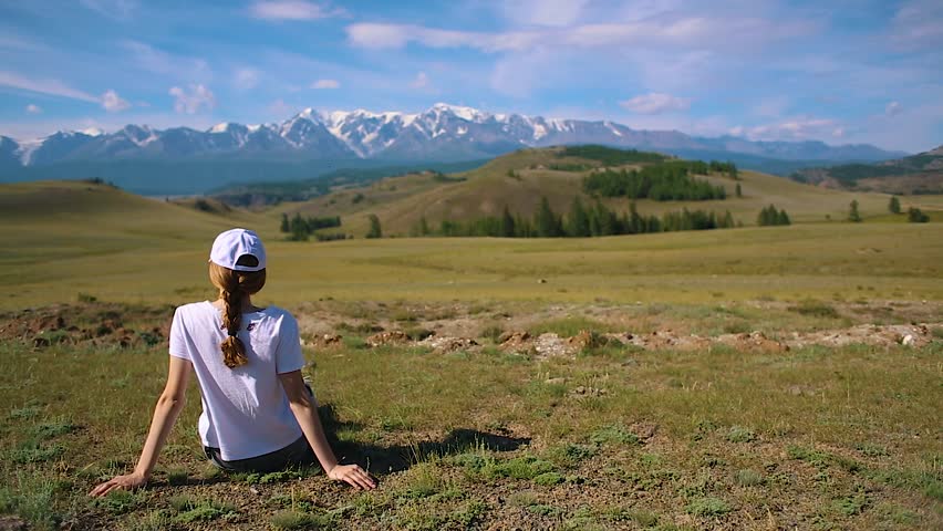 Young Tourist Girl Sit at the Grass Look at the Scenic Mountain Landscape