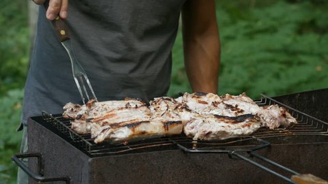 Man prepares grilled meat. Cooking summer BBQ grill steak. Close up, man's hand preparing meat on grill