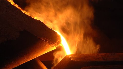 Room for the manufacture of metal products by casting. Casting shop for gassified models. The molten metal is poured from the induction furnace into the ladle. Sparks of hot metal fly apart. Close-up.