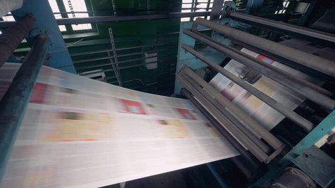 Modern equipment at a printing factory printing newspaper. 4K.