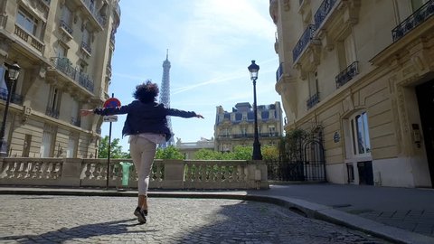 Happy woman enjoy panoramic view of Paris Eiffel Tower walking and jumping on traditional street pavement and old buildings facades