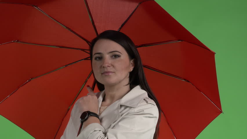 Brunette woman under red umbrella against green screen closeup