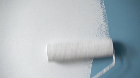 Roller painting blue wall with white paint