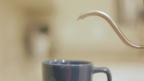 Pouring water from metal tea kettle into cup
