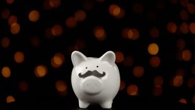 Piggy bank wearing a fake mustache and rotating counterclockwise against a black background with yellow lights, someone puts a coin in a money box, the concept of celebrating a movember. - Powered by Shutterstock - Get 15% off with code: PIKWIZARD15