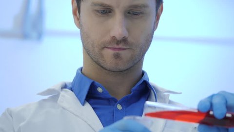 Male medical research scientists mixes smoking liquids in a beakers.
