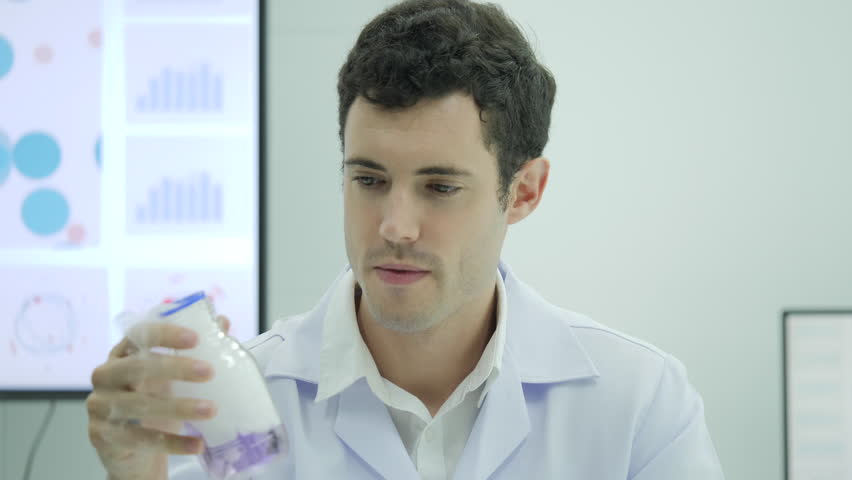 Portrait of Crazy and mad scientist looking and holding laboratory glass bottle with purple liquid.