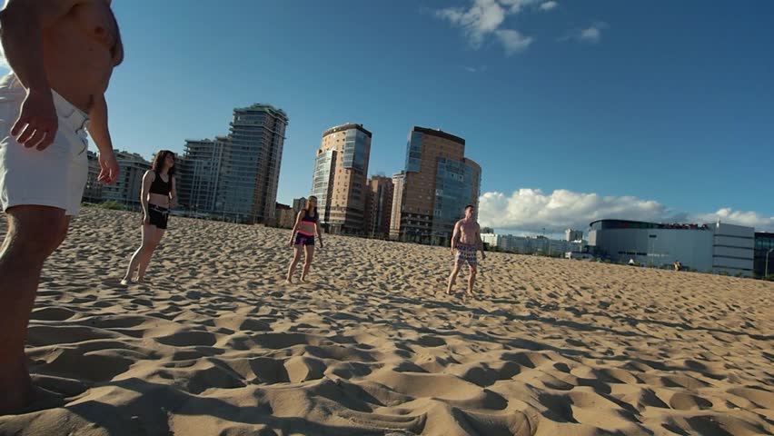 Dynamic game of beach volleyball without a net with cute young guys and girls