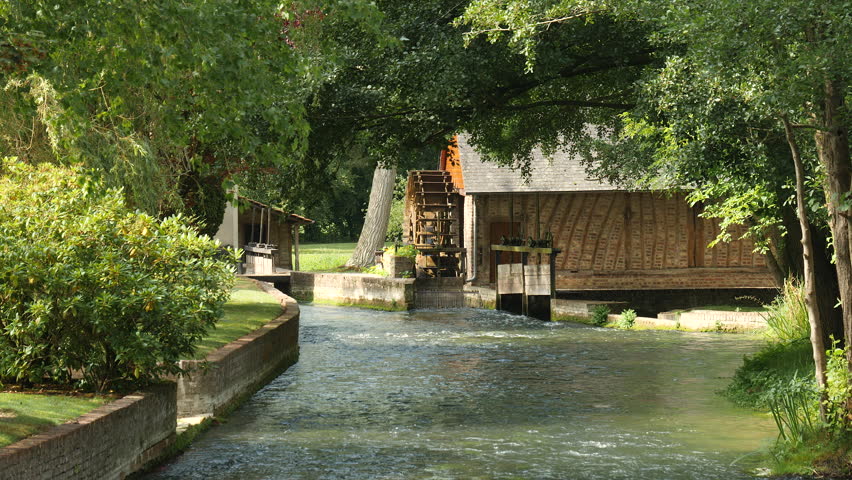 Watermill treading by creek in village in Normandy, France.