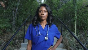 Slow motion of african american woman wearing scrubs and looking at the camera and smiling, out in the outdoors
