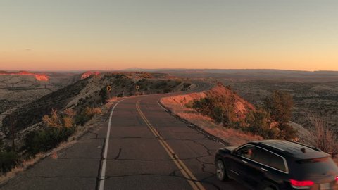 USA, Utah, October 2016, AERIAL: Black SUV car driving along the empty dusty road trough dry meadow desert valley on sunny morning.