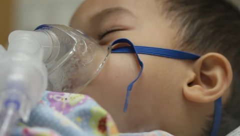 2 years old Asian toddler boy has asthma or pneumonia disease and need nebulizations,Sick boy rest on patient bed and has inhalation therapy by the mask of inhaler.Sick or cancer child awareness.