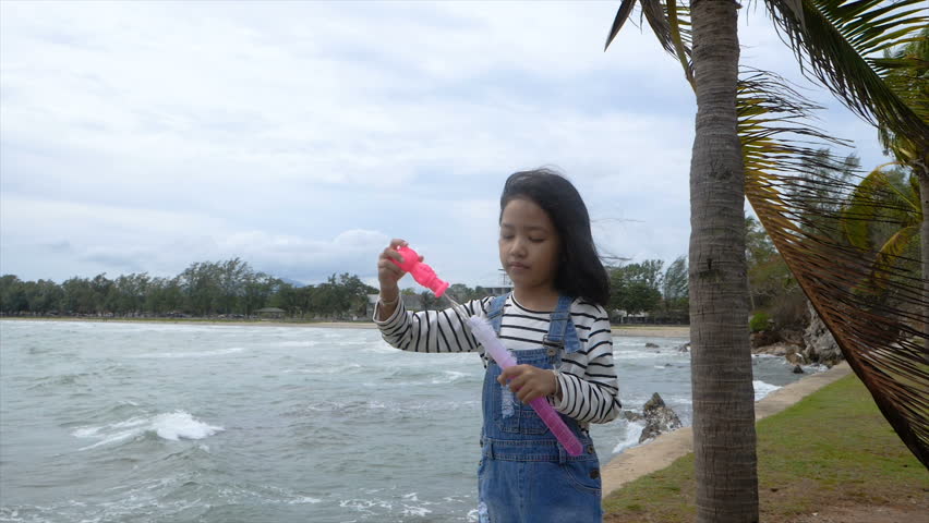 Slow motion Asian little girl playing bubble balloon nearly the beach