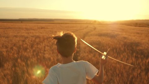 Happy kid run with toy airplane at sunset over wheat field. Kid dreams of becoming an astronaut pilot. Airplane pilot. Children dream to run with toy. Kid airplane pilot. Dream concept. Wheat field