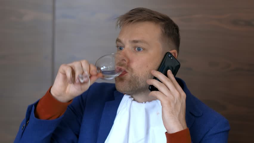 Bearded man chewing food and drinking water from glass during mobile conversation close up. Business man talking to smartphone during lunch in restaurant | Shutterstock HD Video #1015632919