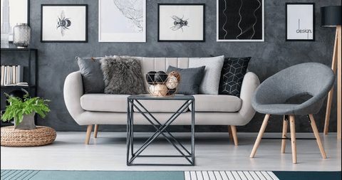 Video of gray, black, blue and red armchairs changing next to a beige sofa with decorative cushions in gray and white living room interior. Stop-motion sequence