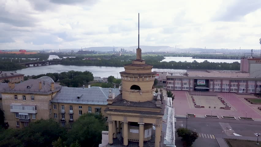 Drone flight around the old classic tower with architectural elements like columns and stucco towering over the architectural ensembles of residential area, smoking pipes of huge factory on background Royalty-Free Stock Footage #1015650424