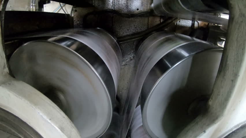 A large webset offset printing press running a long roll off paper over its rollers at high speed