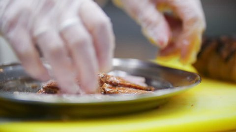 Cook interferes with slices of pork in sauce in bowl
