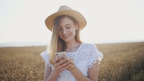 Portrait beautiful woman with hat use phone smile happy girl fashion model in slow motion on field wheat on sunset smartphone countryside female freedom happiness nature outdoor summer slow motion