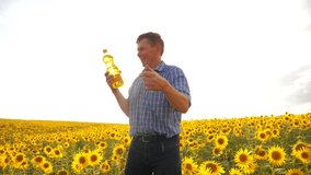 old man sunlight farmer sunflower oil concept agriculture. old man farmer holding in hand a plastic bottle sunflower oil lifestyle stands in the field. slow motion video. sunflower oil production and