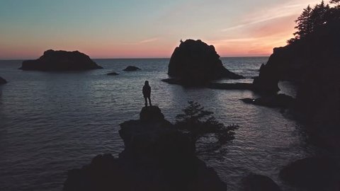 Girl stands on top of sea stack of Oregon coast watching twilight