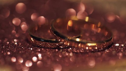 Wedding rings lying on shiny surface shining with light close up macro