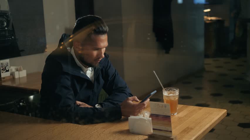 Handsome stylish man leaving message using voice recognition, speaking at smartphone in cafe bar drinking cocktail coffee message helper modern bar voice search