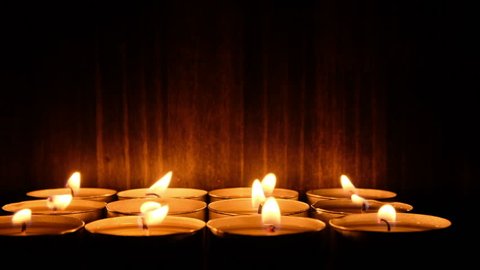 Lit candle tealights against dark background