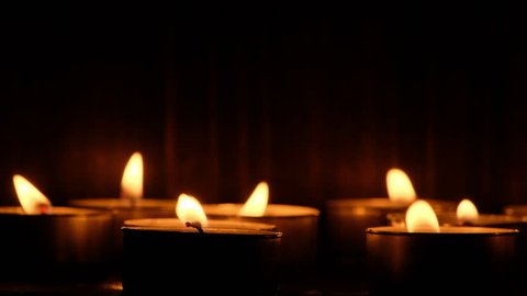 Lit candle tealights against dark background