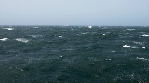 Cargo ship rolling in stormy sea. Huge waves of summer monsoon in Indian Ocean