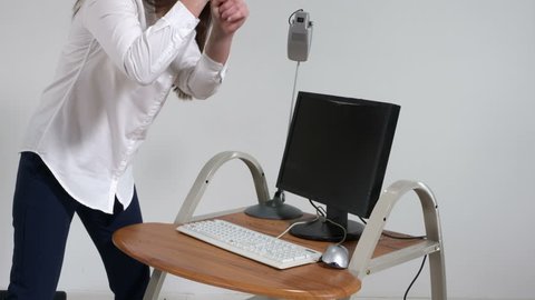 Crazy woman office worker destroying computer with sledge hammer