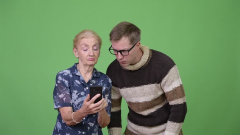 Grandmother and grandson using phone then looking shocked together