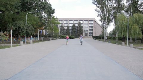HD A Couple riding bicycles in the park, on block stones moving on the camera