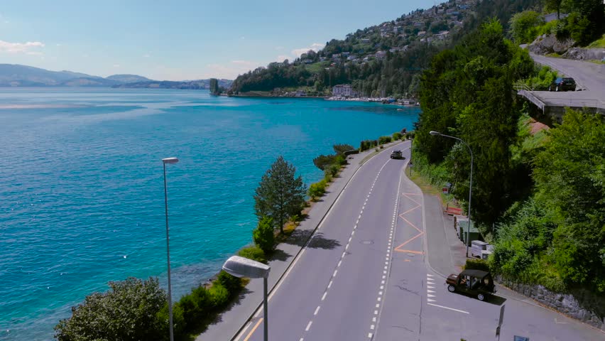 Amazing aerial view of alpine road and lake, Switzerland, Europe. Footage. tourist man with backpack walk, motion on a highway road at Lake. summer road trip, vacation concept