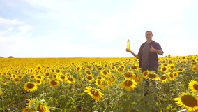 Man farmer hand hold bottle of sunflower oil the field at sunset. man lifestyle shows on the production of sunflower oil in a field at sunset plastic bottle. slow motion video. man farmer agriculture