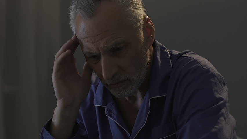 Elderly male sitting on bed in dark room, rubbing his temples, strong headache Royalty-Free Stock Footage #1015698538