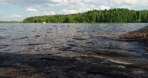 Waves by the lake seen from a cliff with forrest on the other side of the lake on a summer day, Puumala Finland