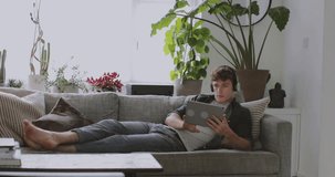 Young adult male listening to music and using a digital tablet