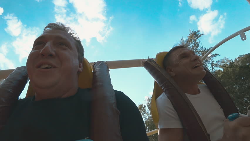 Riding on the carousel. Two men. Fear. Wheel. Upside down. Close-up. Slow motion.