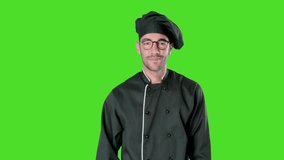 Proud young chef pointing to himself against green background
